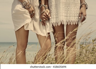 close up of women`s legs in boho style white dresses