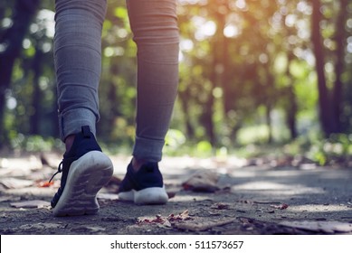 Close Up Of Women's Shoes Walking Outdoors In Running Shoes From Behind.