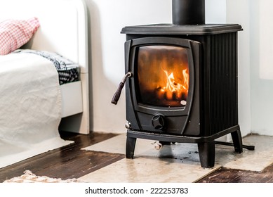 Close up of wood burning stove heating appliance in bedroom flame inside of household equipment. Cozy comfortable for people cold weather easy indoors heating concept