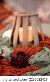 Nahaufnahme der Holzlattern-Hochzeitsdekoration, mit Fokus auf schlängelgrünem, orangefarbenem Stoff und Seidenblumen, künstlicher Blume, unscharfem Hintergrund – Stockfoto