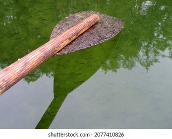 Close Up Of The Wooden Canoe, Kayak Oar Against Clear Green Waters Full Of Fish. Podlasie, Poland, Europe