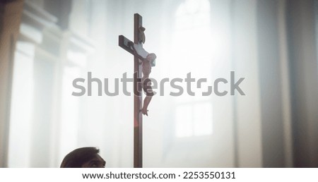 Close Up of a Wooden Cross with Statue of Jesus Christ's Crucifixion. Representation of the Lord's Kindness and Sacrifice for Humanity. God's Light Shining Upon Him from the Church's Window