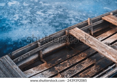 Close up of a wooden rowboat on the frozen lake.	