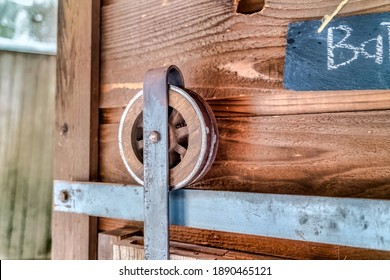 Close Up Of The Wooden Wheel And Metal Track Of A Rustic Bathroom Sliding Door