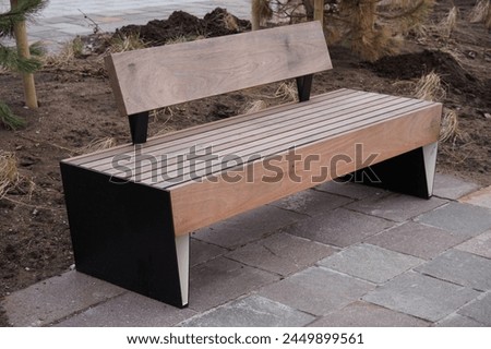 Close up of wooden wide brown bench. Stone paving on the ground. Place for rest and relax. No people.