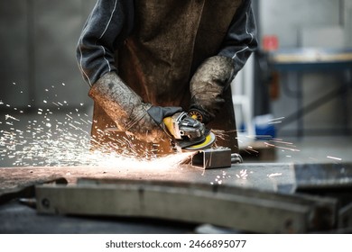 Close up of work of welder in workshop, operating welding machine, wearing protective clothing and a welding mask.