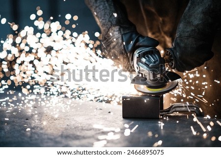 Close up of work of welder in workshop, operating welding machine, wearing protective clothing and a welding mask.
