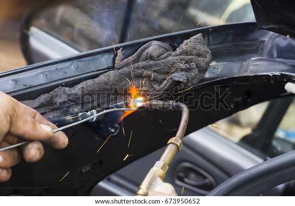 Close up work with\
welding equipment - welding car body. (using gas welder without\
safety equipment)
