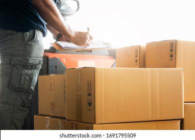 Close up worker courier holding clipboard writing on checklist for delivering shipment pallet goods, package boxes , packaging, cargo export, industry warehouse logistics.