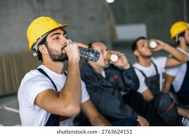 Close up of worker drinking water while coworkers in suits have coffee break in background