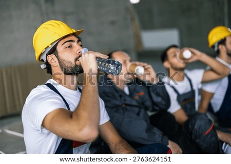 Close up of worker drinking water while coworkers in suits have coffee break in background