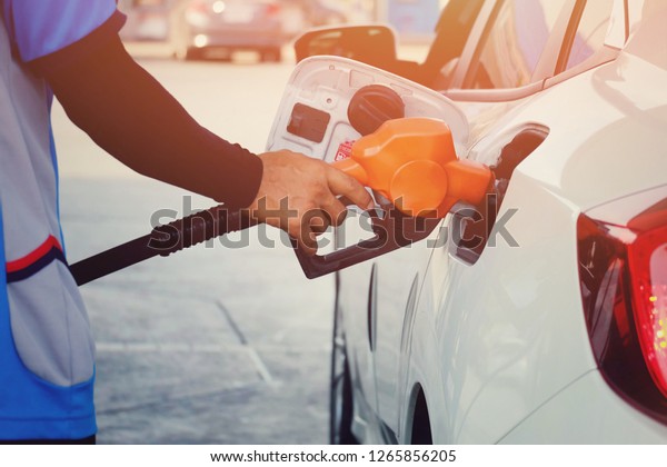 close up worker hand holding nozzle\
fuel for fill oil into car tank at pump gas station, transport\
energy, transportation power business technology concept\
