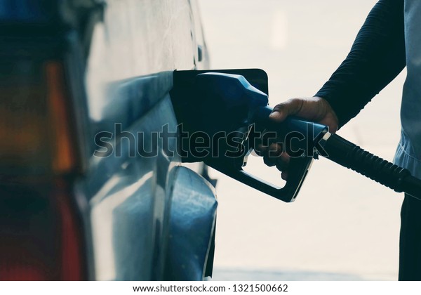 close up worker hand\
holding nozzle fuel fill oil into car tank at pump gas station,\
transport energy, transportation power business technologu concept,\
vintage tone