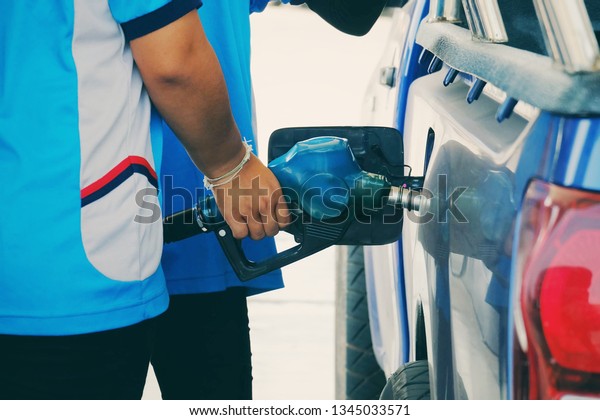 close up worker hand holding nozzle\
fuel fill oil into car tank at pump gas station, transport energy,\
transportation power business technology\
concept