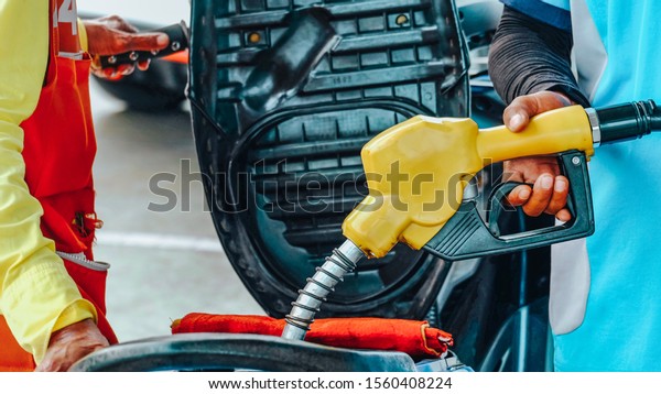 Close up worker\
hand holding nozzle fuel fill oil into motorcycle tank at pump gas\
station, transport and energy, transportation power business\
technology concept, vintage\
tone