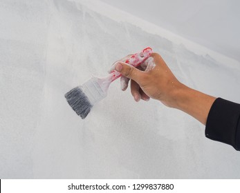 Close Up Of Worker Hand Useing Roller And Brush For Painting Wall. House Building Concept.