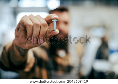 Close up of worker holding screw. Selective focus on fingers with a screw. Worker's tool. Worker in the shop