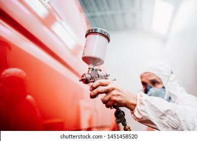 close up of worker painting a red car in a special garage, wearing a white costume - Powered by Shutterstock