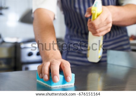 Close Up Of Worker In Restaurant Kitchen Cleaning Down After Service