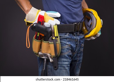 Close up of a worker with toolbelt and helmet against black background