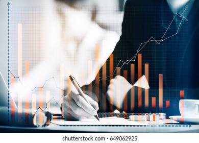 Close up of worker's hand doing paperwork at workplace with business chart. Accounting concept