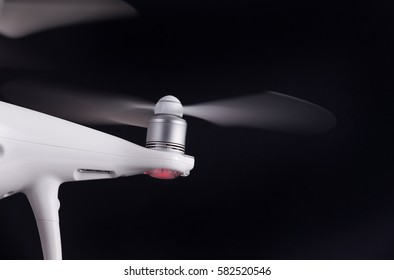 Close up of working propeller of white drone against black background
