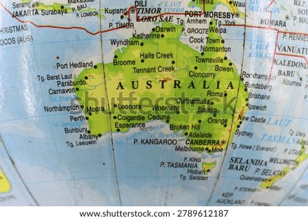 Close up of a world globe map focusing on Australia continent and Oceania region, educational geography concept.
​A close-up macro shot of a physical world globe focusing entirely on the Australian continent, including major cities like Canberra, Sydney, Melbourne, and Perth. The map is labeled in the Indonesian language, making it ideal for educational materials, geopolitical design, travel planning, or regional geography lessons in Oceania.