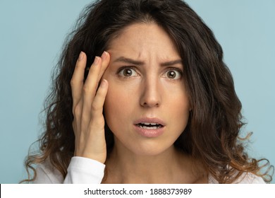 Close Up Of Worried Woman Without Makeup Has Signs Of Aging Skin, Checking Crows Feet Troubled With Wrinkles On Face, Afraid Of Getting Old, Looking At Camera, Isolated On Studio Blue Background. 