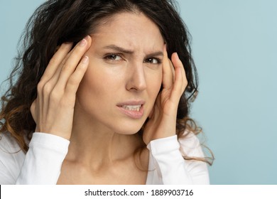 Close Up Of Worried Woman Without Makeup Has Signs Of Aging Skin, Checking Crows Feet Troubled With Wrinkles On Face, Afraid Of Getting Old, Looking At Camera, Isolated On Studio Blue Background. 