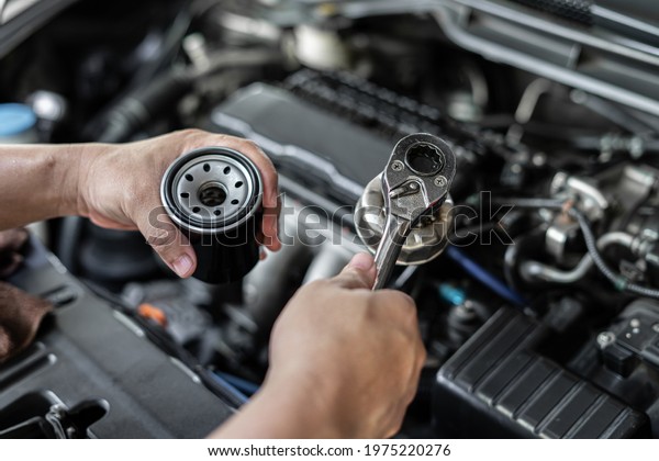 Close up wrench in hand a man with\
oil filter change in engine room service concept of\
car
