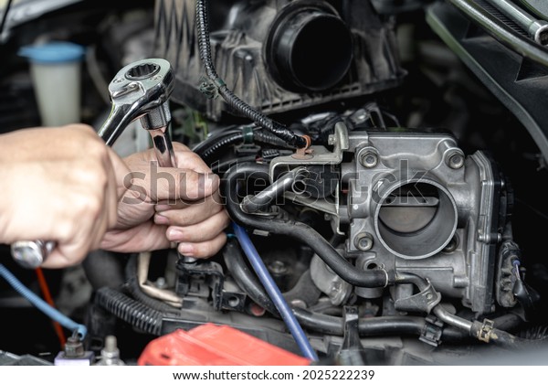 Close up wrench in hand a man  remove bolt\
of engine in car service engine throttle valve cleaning and\
maintenance : car service concept\
photo