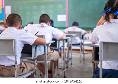 Close Up Of Writing Test In Exam With Behind Child Asian Students Group Concentrate In Primary School, Final Examination Desk At Classroom With Thai Student Uniform, Education Evaluation Concept