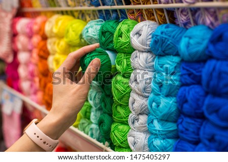 Close Up of yarn balls. Girl hand choosing Yarn in Knitting Shop. knitting shop center. A lot of color yarn for knitting. Selection of colorful yarn wool on shopfront