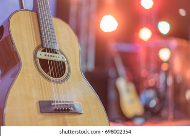 Close Up Yellow Acoustic Guitar On A Stand In Front Of A Stage Set Up For An Upcoming Concert.