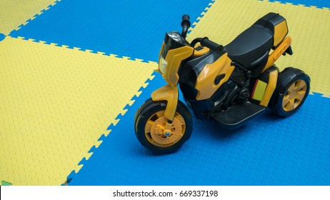 Close up of yellow motorcycle toy on rubber floor with copy space at playground. Cute little motorcycle on safe zone for kids with blank space for text.