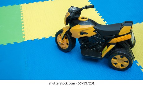 Close up of yellow motorcycle toy on rubber floor with copy space at playground. Cute little motorcycle on safe zone for kids with blank space for text.