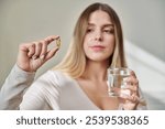 Close up of yellow omega 3 fish oil capsule in hand of young woman.