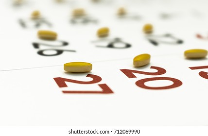 Close up of yellow pills on a calendar. Medication plan, schedule, list or calendar concept. - Powered by Shutterstock