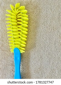 Close Up Yellow Plastic Cleaning Brush with Blue Handle Laying on Brown Towel, Used Wet with Wwater or Ccleaning Fluids.