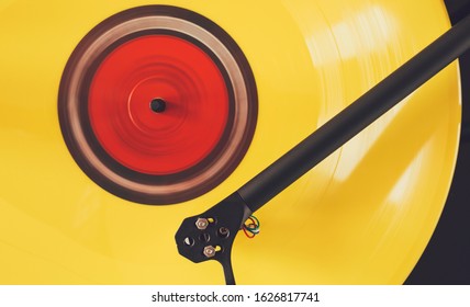 Close up of yellow vinyl record playing. Turntable tonearm and color vinyl record