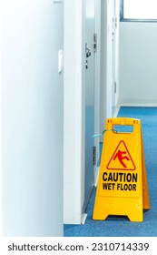 Close up yellow warning sign janitorial janitor works with message Caution Wet Floor with copy space - Shutterstock ID 2310714339