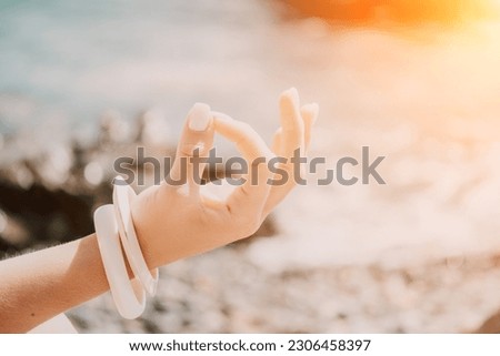 Close up Yoga Hand Gesture of Woman Doing an Outdoor meditation. Blurred sea background. Woman on yoga mat in beach meditation, mental health training or mind wellness by ocean, sea