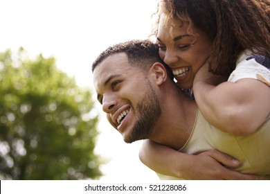 Close up of young adult couple piggybacking outdoors, side view - Powered by Shutterstock