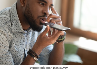 Close up of young african American man hold cellphone talk using virtual digital voice assistant, siri activation, biracial male speak on speakerphone loudspeaker on smartphone, record audio message - Powered by Shutterstock