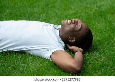 a close up young african american person lying and chilling on the grass in the park - Powered by Shutterstock