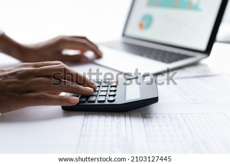 Close up young african american woman using calculator, managing business expenses, making financial audit, reviewing utility bills taxes, planning household monthly budget, accounting in computer app