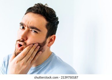 close up of a young american man touching mouth with hand with painful expression because of toothache or dental illness on teeth. Dentist concept.