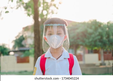 Close Up Of Young Asian Boy Wearing Mask And Face Shield Against The Corona Virus Covid 19, Asian Student Wearing Surgical Mask And Face Shield To Prevent From Virus In The Park,face Close Up