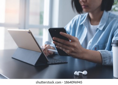 Close Up Of Young Asian Business Woman Using Mobile Smart Phone,  Working On Laptop Computer, Digital Tablet In Modern Home Office. Female Entrepreneur Online Working, Searching Internet Via Laptop.