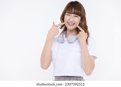 Close up young Asian girl smile and pointing finger to her teeth with braces isolated on white background. Dental care concept. - Powered by Shutterstock